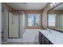 Bathroom featuring double sinks, a shower with glass door, a garden tub, and natural light from a window at 25386 W Darrel Dr, Buckeye, AZ 85326
