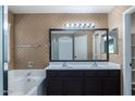 Bathroom featuring double sinks, a tub, and warm wall paper at 25386 W Darrel Dr, Buckeye, AZ 85326