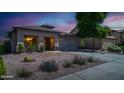 Charming single-story home with desert landscaping, gravel yard, and lush green bushes under a colorful sky at 25386 W Darrel Dr, Buckeye, AZ 85326