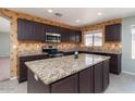 Bright kitchen with granite counters, stainless steel appliances, tile floors, and a large central island at 25386 W Darrel Dr, Buckeye, AZ 85326