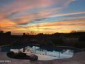 The backyard pool at sunset features a rock waterfall with beautiful desert landscape views at 42102 N Long Cove Way, Phoenix, AZ 85086