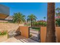 Private courtyard featuring a stone wall with fountain, a metal gate, and desert landscaping at 5434 E Lincoln Dr # 58, Paradise Valley, AZ 85253