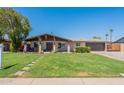 Charming single-story home boasting a lush green lawn, inviting covered porch, and convenient two-car garage at 6244 W Clouse Dr, Phoenix, AZ 85033