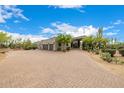 Wide circular driveway leads to a desert home featuring three garage doors and native landscaping at 9627 E Adobe Dr, Scottsdale, AZ 85255
