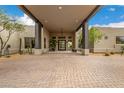 Inviting covered home entrance with stone pillars, desert plants, and elegant exterior lighting at 9627 E Adobe Dr, Scottsdale, AZ 85255