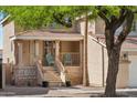 Inviting front porch with neutral stone accents, charming railings, steps, and ample seating, under the shade of mature tree at 991 W Leah Ln, Gilbert, AZ 85233
