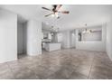 Open-concept living room featuring tile flooring, a ceiling fan, and seamless flow to the kitchen at 11505 W Boca Raton Rd, El Mirage, AZ 85335