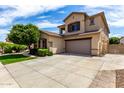 Two-story home featuring desert landscaping, a large driveway, two-car garage, and neutral color scheme at 13259 W Flower St, Litchfield Park, AZ 85340