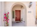 Covered front entry featuring an arched entryway, red door, desert plants, and house number at 16017 N 19Th Dr, Phoenix, AZ 85023
