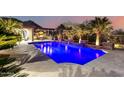 Beautiful backyard pool with water features, mature landscaping, and outdoor kitchen area at twilight at 16201 S 29Th Ave, Phoenix, AZ 85045