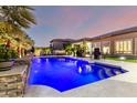 Stunning pool with lights set in a private backyard and views of the home's exterior and manicured landscaping at 16201 S 29Th Ave, Phoenix, AZ 85045