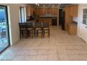 A spacious kitchen features wooden cabinets, a tiled floor, and a long center island with bar stool seating at 207 E Papago Dr, Tempe, AZ 85288