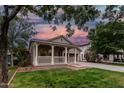 Inviting single-story home featuring a charming front porch and lush green lawn at dusk at 20866 W Hamilton St, Buckeye, AZ 85396