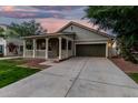 Welcoming single-story home boasting a charming front porch and spacious driveway at dusk at 20866 W Hamilton St, Buckeye, AZ 85396