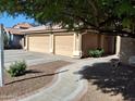 Landscaped front yard with walkway leading to the home's entrance and a three-car garage at 2434 S Colleen --, Mesa, AZ 85210