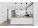 Open kitchen layout with stainless steel appliances, white cabinets, and stylish pendant lighting at 9728 E Twinkle Ave, Mesa, AZ 85212