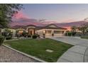 Charming home with three-car garage, desert landscaping, and warm exterior lighting at sunset at 11511 E Chestnut Ct, Chandler, AZ 85249