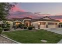 Charming home with three-car garage, desert landscaping, and warm exterior lighting at sunset at 11511 E Chestnut Ct, Chandler, AZ 85249