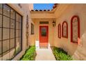 Inviting entryway with a striking red front door, decorative wall accents, and manicured greenery at 1700 E Lakeside Dr # 64, Gilbert, AZ 85234