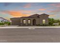 Stunning exterior with warm tones, red tile roof, desert landscaping, and a sunset sky backdrop at 17279 W Dartmouth St, Surprise, AZ 85388