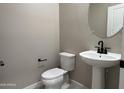 Stylish powder room featuring a pedestal sink with black fixtures and modern accents for guests' convenience at 17482 W Fulton St, Goodyear, AZ 85338