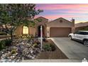 Charming home exterior featuring desert landscaping, a two-car garage and sunset sky at 26725 W Marco Polo Rd, Buckeye, AZ 85396