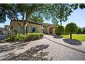 A distinguished home featuring a paver driveway, lush landscaping, and manicured green lawns at 6997 E Paradise Ranch Rd, Paradise Valley, AZ 85253