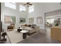 Bright living room boasts large windows, high ceiling, sleek furniture, and an open layout leading to dining area at 16215 W Durango St, Goodyear, AZ 85338
