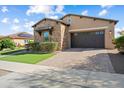 Two-car garage with stone and stucco facade, paver driveway, and manicured landscaping at 20759 W Meadowbrook Ave, Buckeye, AZ 85396