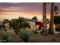 Sunset view of a beautiful desert home with palm trees and bright bougainvillea accenting the front entrance at 10380 E Cholla St, Scottsdale, AZ 85260