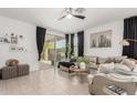 Comfortable living room featuring tile floors, neutral decor, stylish curtains, and a sliding glass door to the patio at 14114 W Surrey Dr, Surprise, AZ 85379