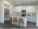 Modern kitchen featuring white cabinets, stainless steel appliances, and a breakfast bar with seating at 17983 W Sand Hills Rd, Surprise, AZ 85387