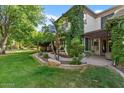 Spacious backyard featuring mature trees, lush green grass, a covered patio, and manicured landscaping at 3011 E Morrison Ranch Pkwy, Gilbert, AZ 85296