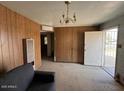 A simple living room featuring wood paneling, outdated furniture, and an exterior door at 3155 E Mobile Ln, Phoenix, AZ 85040