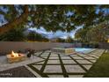Expansive backyard with a stylish fire pit, pool with fountains, and cozy seating area at 4300 S Marble St, Gilbert, AZ 85297