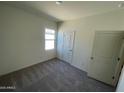 Bedroom with neutral colored walls, carpet flooring, a window and two doors at 13226 E Verbina Ln, Florence, AZ 85132