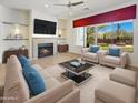 Bright living room with fireplace, ceiling fan, stylish furniture, and large windows showcasing desert landscaping at 30224 N 52Nd Pl, Cave Creek, AZ 85331