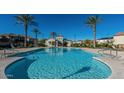 Gorgeous community pool with palm trees, lounge chairs, and a building with a bathroom at 30876 N 128Th Dr, Peoria, AZ 85383
