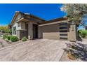 Beautiful single-story home featuring a large front-facing three car garage and a brick paved driveway at 5233 N 207Th Dr, Buckeye, AZ 85396