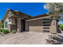 Beautiful single-story home featuring a large front-facing three car garage and a brick paved driveway at 5233 N 207Th Dr, Buckeye, AZ 85396