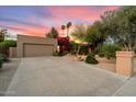 Spacious driveway leading to a tan home featuring desert landscaping, mature trees, and vibrant bougainvillea at 5334 E Everett Dr, Scottsdale, AZ 85254
