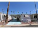 Inviting manufactured home with covered carport, palm trees, and desert landscaping at 7807 E Main St # F-35, Mesa, AZ 85207