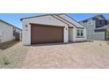 Picture of the house showing the neutral-toned stucco, brown trim, paver driveway, and two car garage at 9547 W Parkway Dr, Tolleson, AZ 85353