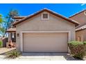 Tan home with a large two car garage, tile roof, desert landscaping, and a bright blue sky at 10225 W Camelback Rd # 3, Phoenix, AZ 85037