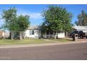 A cozy home with a lush front yard, framed by mature trees and a clear blue sky at 14439 N 38Th Pl, Phoenix, AZ 85032