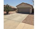 Charming single-story home featuring a two-car garage and desert landscaping at 15023 W Redfield Rd, Surprise, AZ 85379