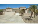 Tan home featuring a three car garage, desert landscaping, and palm trees at 15211 N 184Th Ct, Surprise, AZ 85388
