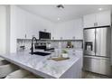 Modern kitchen with sleek, white cabinets, stainless steel appliances, and a spacious marble countertop island at 1961 N Hartford St # 1162, Chandler, AZ 85225
