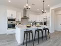 Bright kitchen with white cabinets, stainless steel appliances, large island with seating and stylish pendant lighting at 6564 W Apex Ave, Queen Creek, AZ 85144