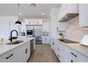 Modern kitchen featuring white cabinets, stainless steel appliances, and a white stone backsplash at 6579 W Apex Ave, Queen Creek, AZ 85144